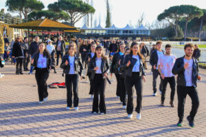Il gruppo Dinamikclub avanza sorridente verso il pubblico durante lo spettacolo all'Ippodromo di Pisa